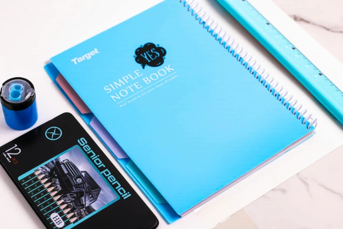 A notebook, pen, and other items on a table